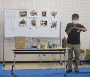 講師がホワイトボードを見ながらマグカップの作り方を説明している。