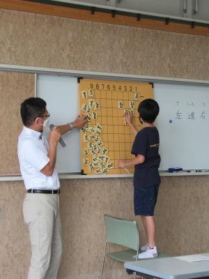 プリント学習の解答を、前に出て大きな将棋盤で説明している様子。
