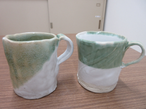 白地に淡い緑色のマグカップ２個。緑色の釉薬の付け方で印象が違います。