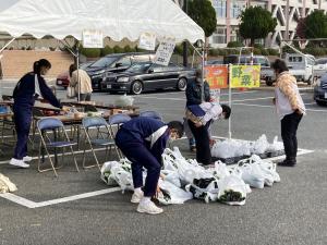 野菜バザーを手伝う中学生ボランティアと買い物客の様子