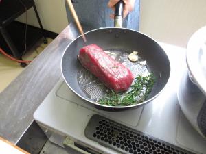 フライパンで牛肉の塊を焼く写真